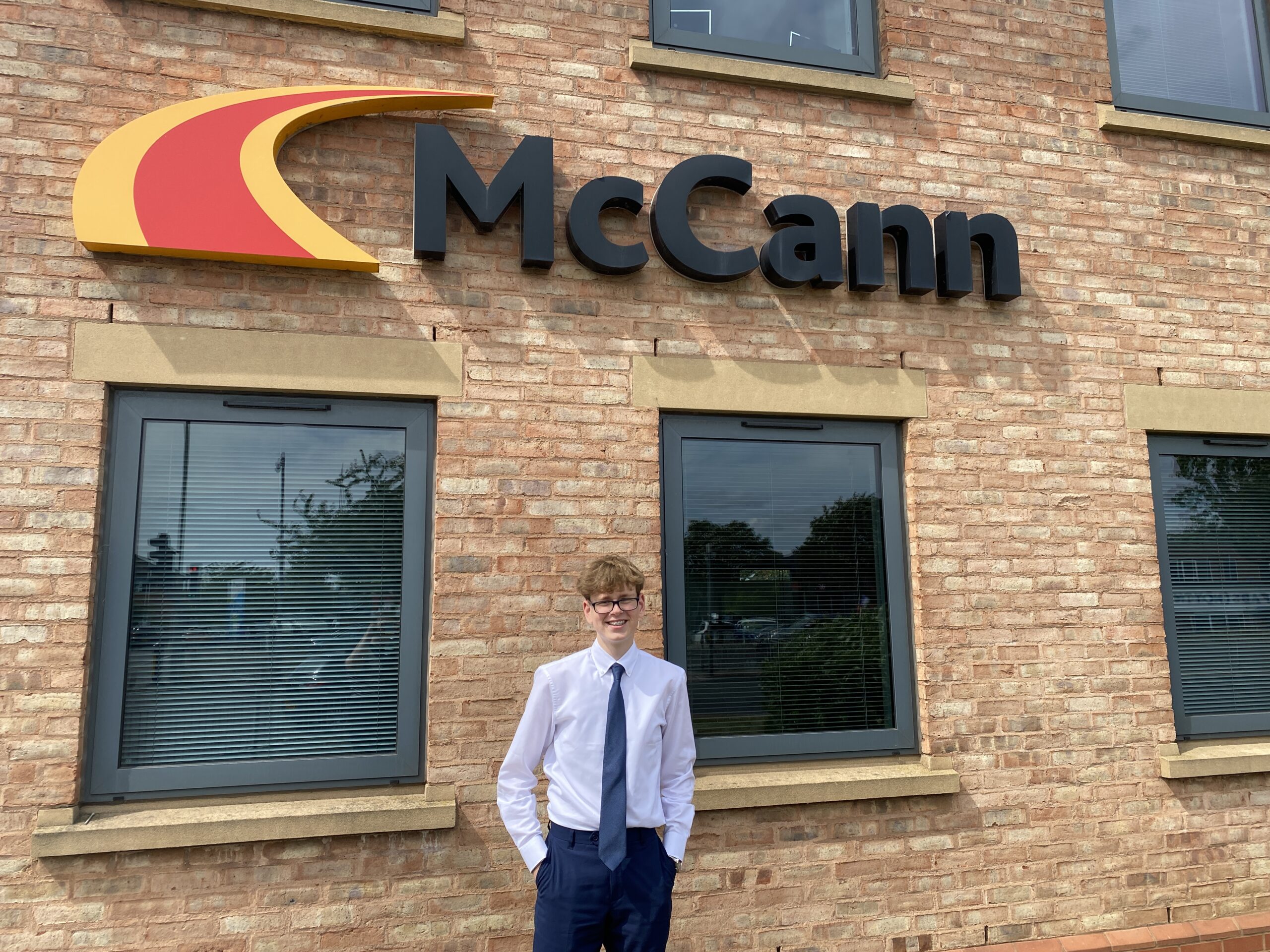 photo of taylor who undertook work experience at mccanns, stood by the head office building sign